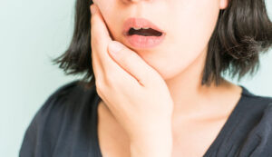 女性が頬を抑えている